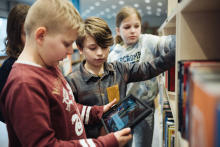 Børn med tablet foran bogreol