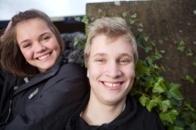 En glad dreng og en glad pige billedet skal symbolisere to elever, som er glade for, at de skal til afsted til et af Skoletjenestens tilbud